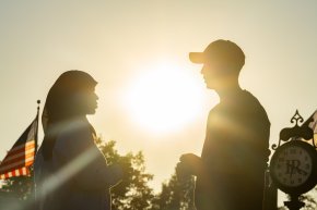 Silhouette of two students facing each other outside during sunset