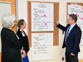 Dr. Lowry pointing out information on a board to colleagues
