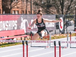 Lacey Triplett jumps over hurdles during an outdoor match