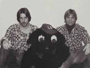 Two people sitting with bear mascot costume