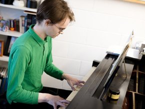Dan Paradis plays piano in a practice space 