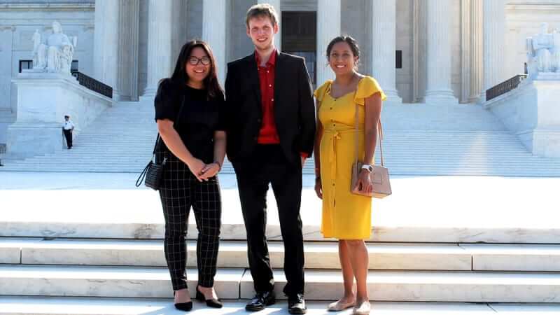 Three student interns in front of the supreme court building
