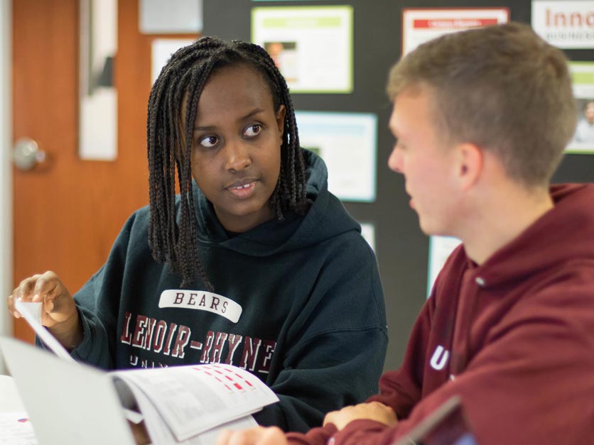 Two students talking while working in classroom on class assignment