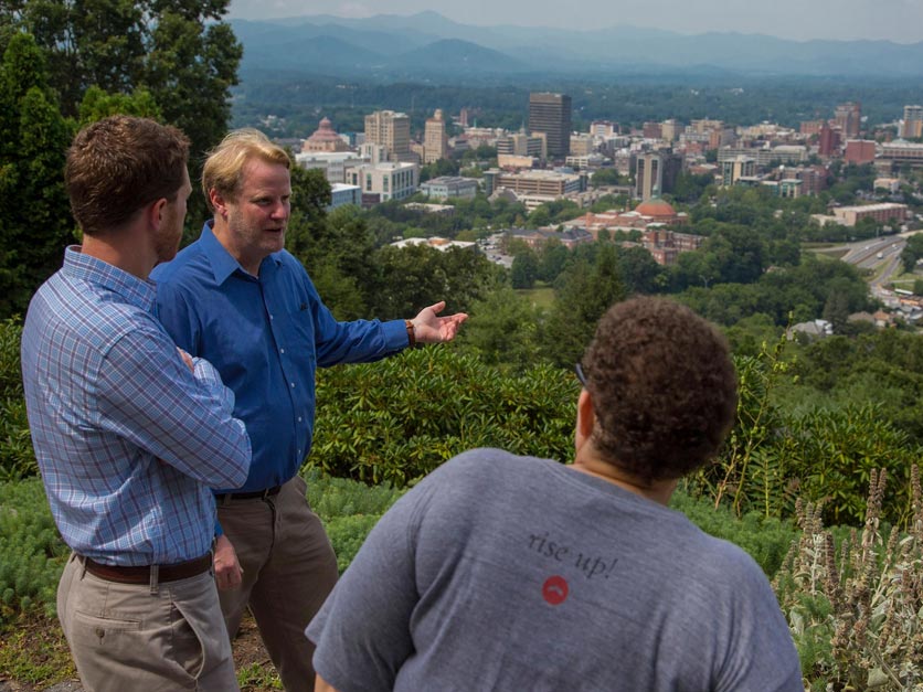 Two students talk with professor while overlooking City of Asheville