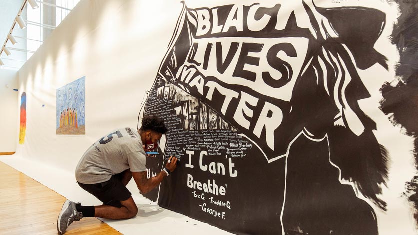 Student paints Black Lives Matter mural on wall at local art center