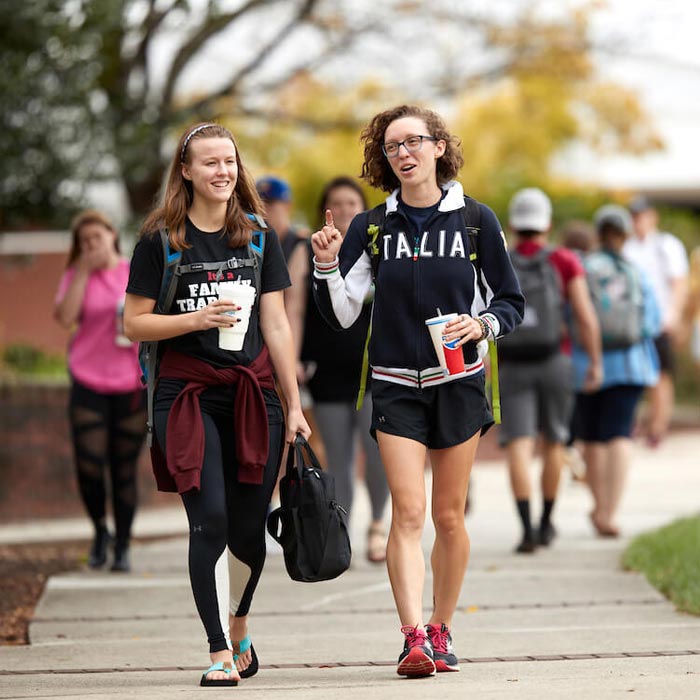 Two students talking as they are walking across campus at LR
