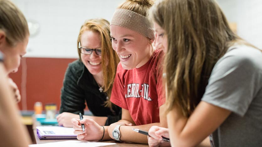 Group of smiling students working on class project at table