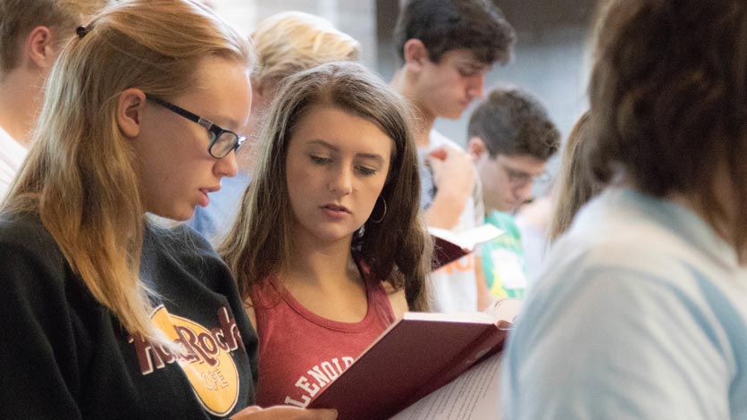 Students reading from booklet during church service