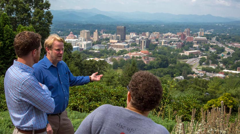 Professor talks to two students while overlooking City of Asheville skyline