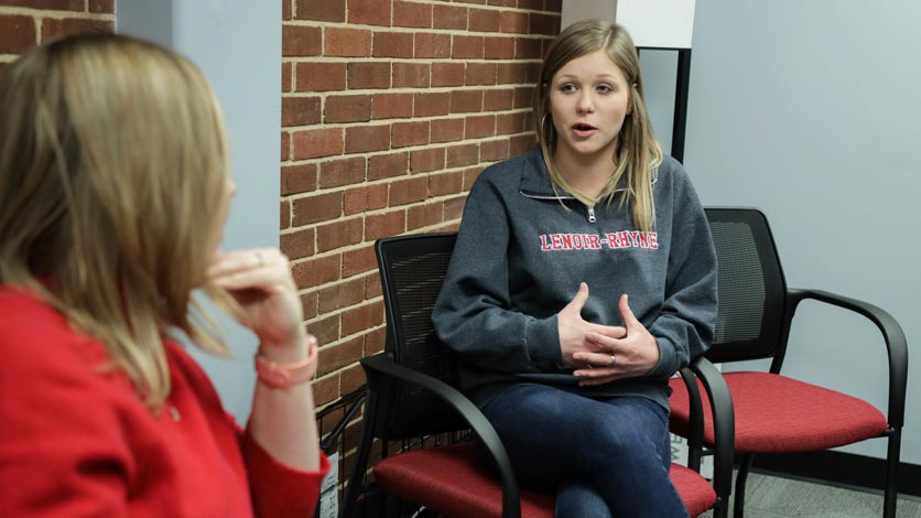 Student talks with invited speaker during group gathering