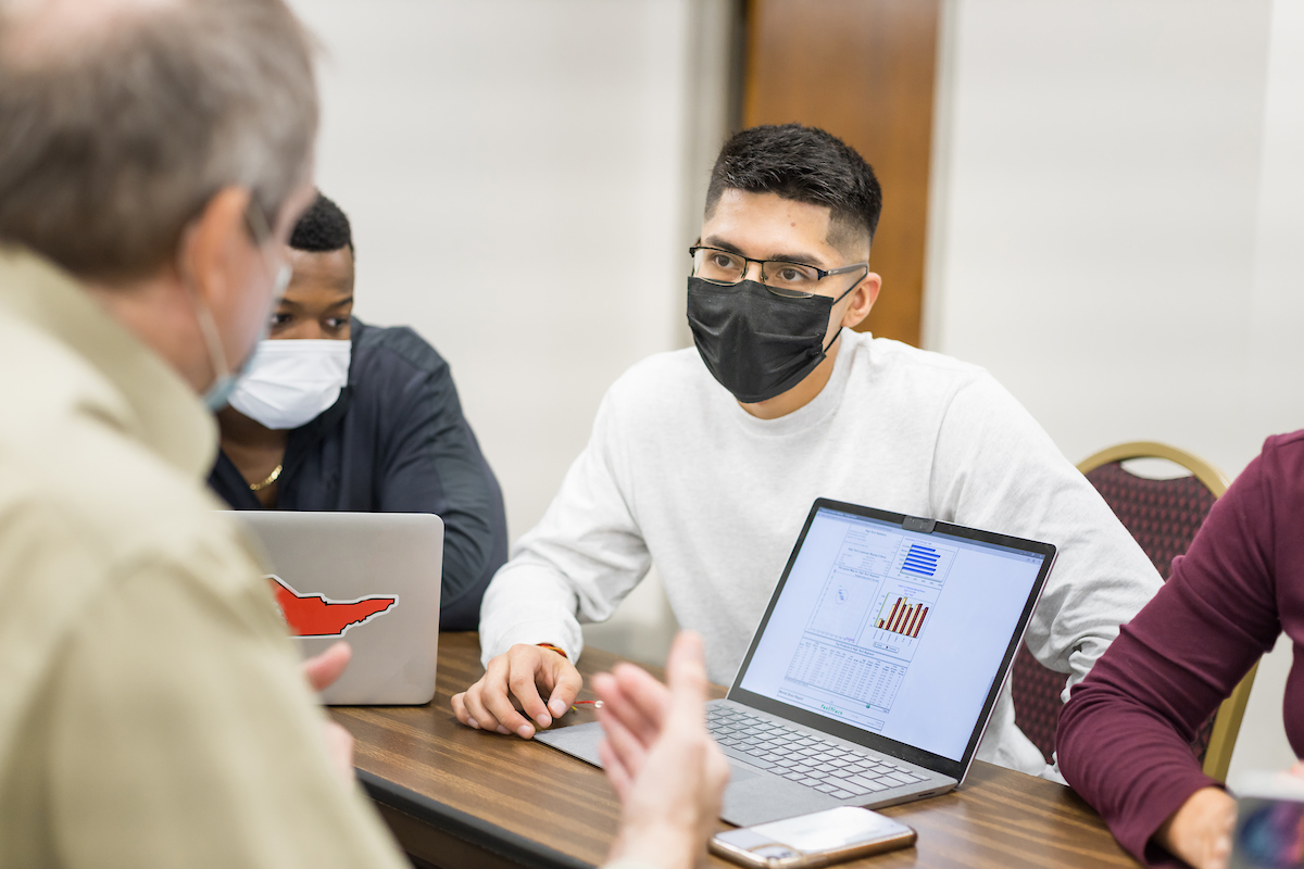 Moises Vazquez interacts with a professor inside a classroom