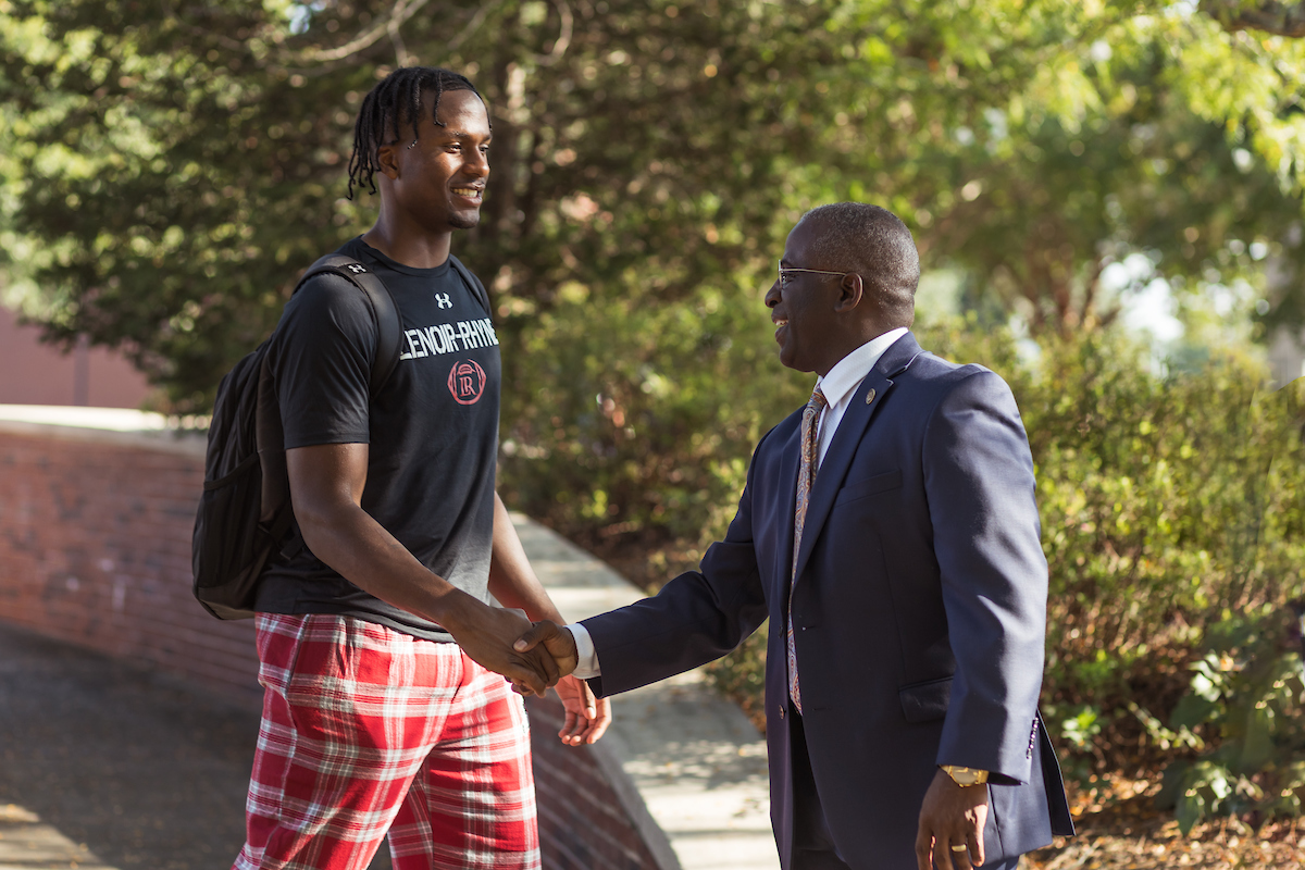 Avery Staley, right, shakes hands with a student, left, outside on campus.