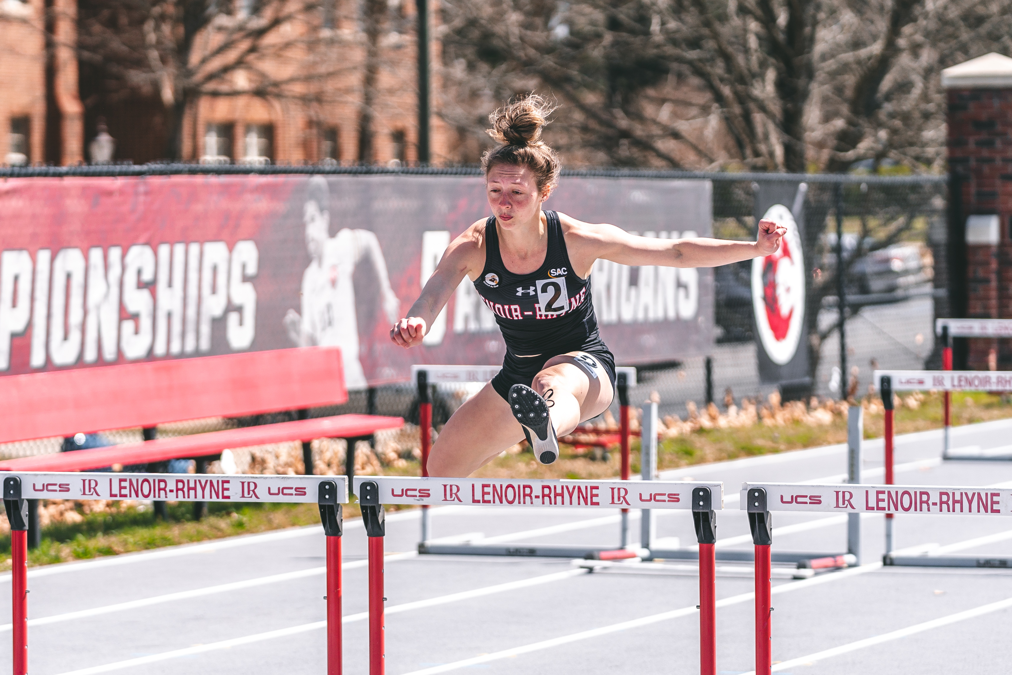 Lacey Triplett jumps over hurdles during an outdoor match