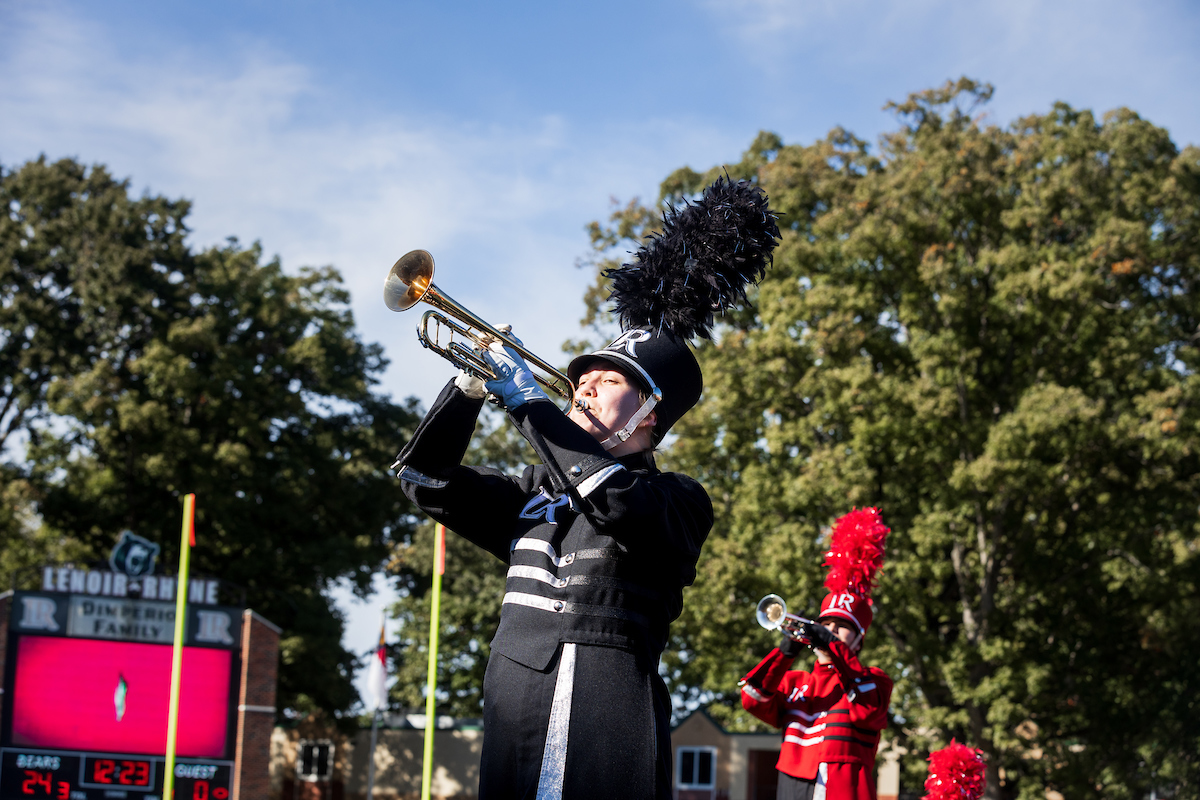 Members of the marching band play trumpets outside on the football field