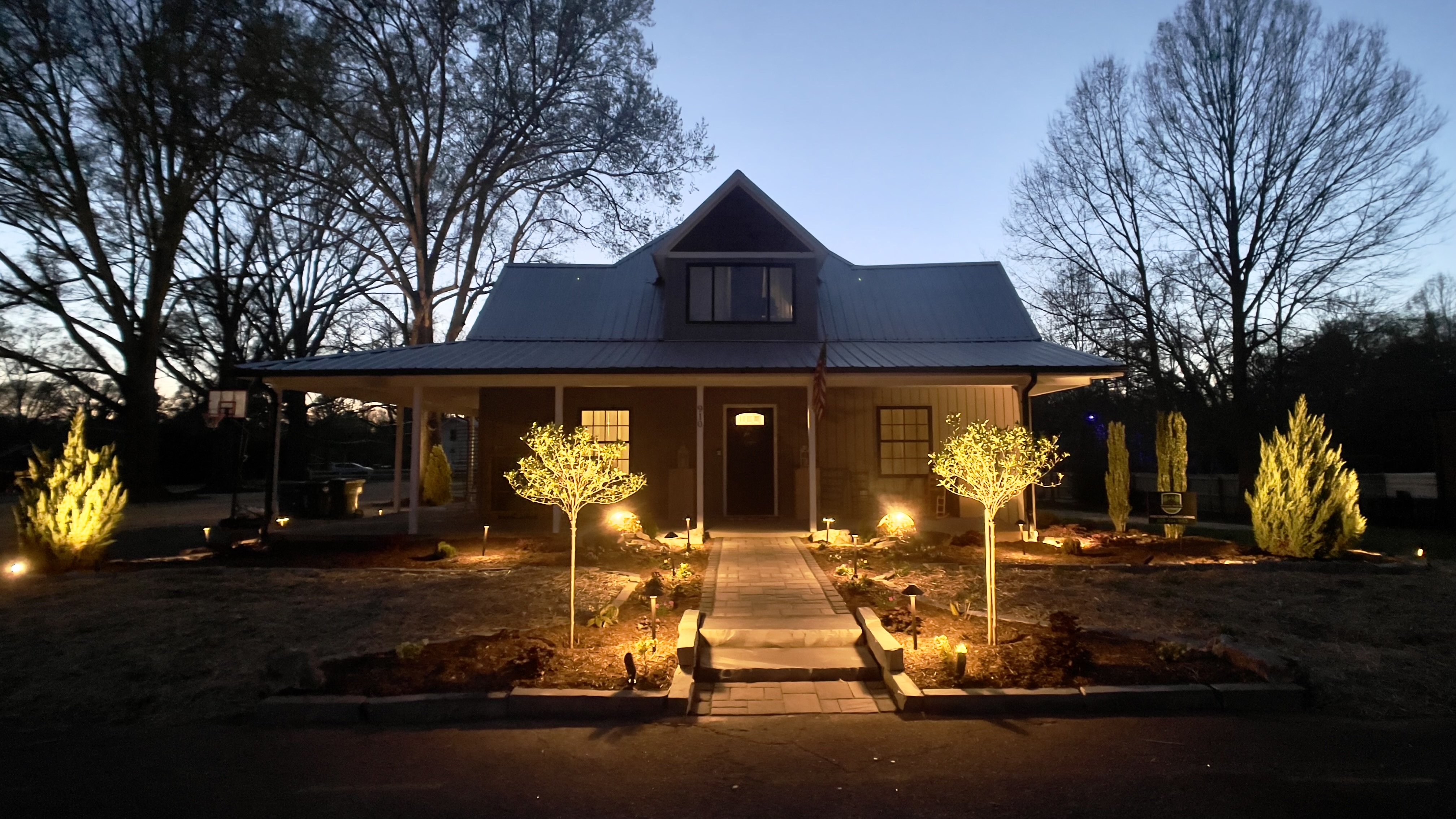 A home is photographed at dusk with additional uplighting on
