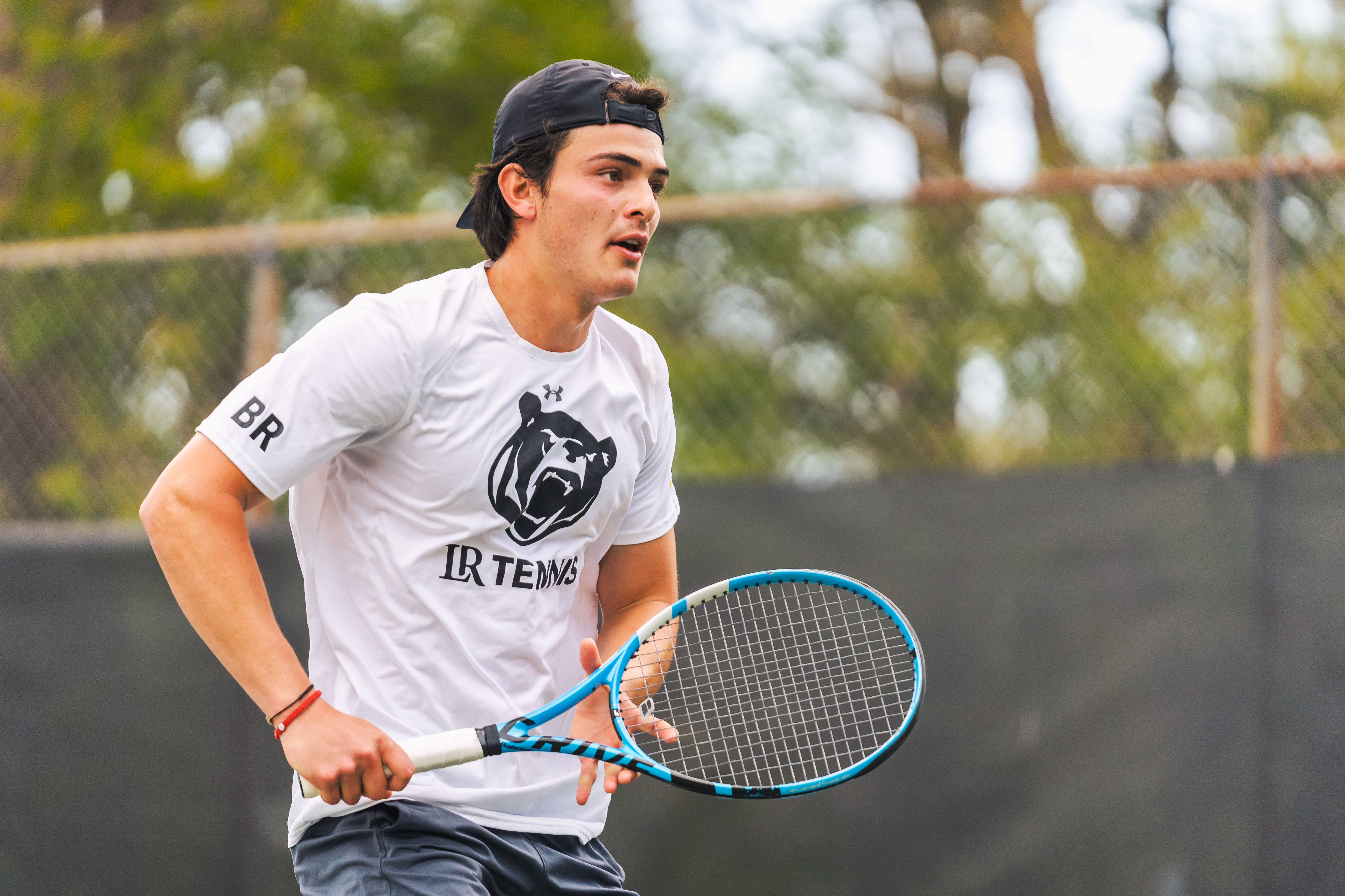 Mauricio Hernandez holds a tennis racket outside