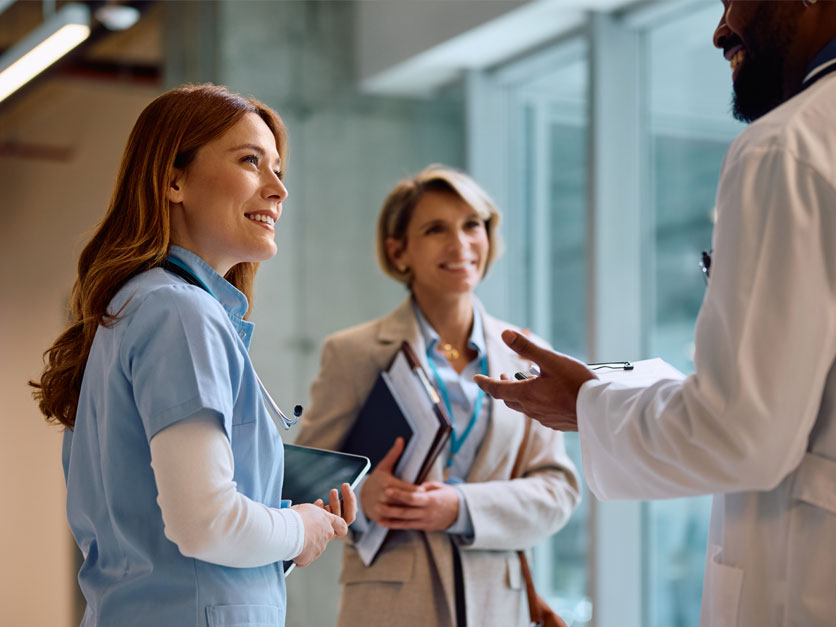 Healthcare administrator talks with colleagues in hospital hallway