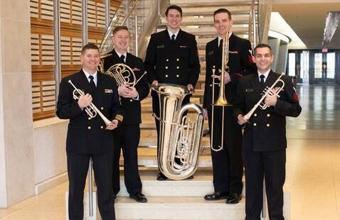 U.S. Naval Band Wind Ensemble pose with instruments in front of stairway
