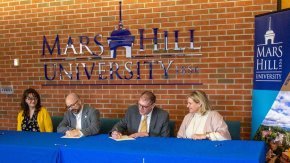 Administrators from Lenoir-Rhyne University and Mars Hill University sign partnership agreement at table
