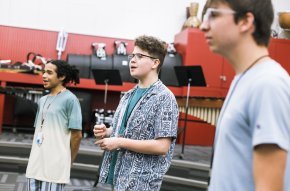 Three students sing in an indoor classroom