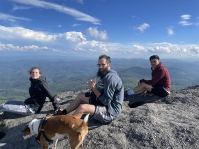 Three students and a dog sit atop a rocky range after a mountain hike
