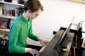 Dan Paradis plays piano in a practice space