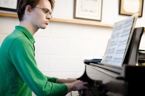 Dan Paradis looks thoughtful as he sits at the piano and reads music