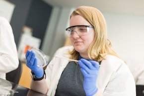 Sabrina Fredo placing a sample in a petri dish in a microbiology lab