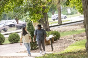 Two students walk together across the main quad