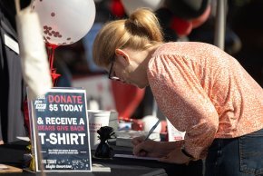 A student signs a form to make a donation at a table on Shaw Plaza