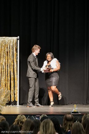 SGA president Isaac Riggs presents an award on the stage next to a gold curtain