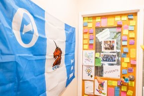 The door to Toni Oakes' office covered with post-it notes from students, Theta Xi flag to the left