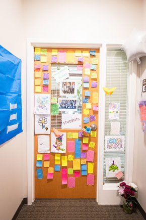 Long shot showing the full door to Toni Oakes' office with multicolored post-its on all available space