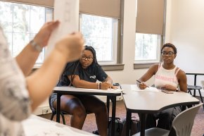 Two students observe the hands of a professor in the foreground as they gesture during a lecture