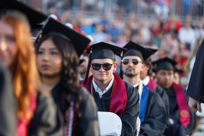 Students sitting on the Moretz field during graduation