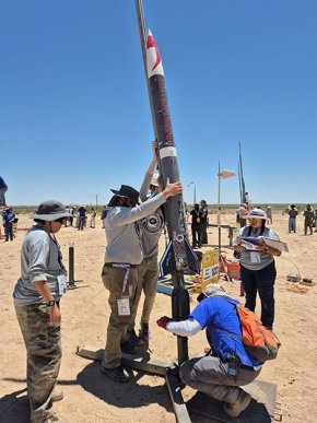 Five rocket team members move their 2025 rocket into vertical position for launch