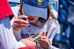 A rocket team member uses a screwdriver to adjust a component before launch