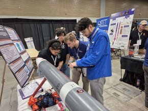 Four rocket team members set up their display in the exhibition at the IREC in Midland Texas