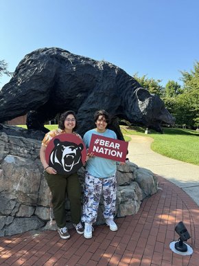 Christina Fisher and Demmi Ramos hold LR spirit signs in front of The Charge