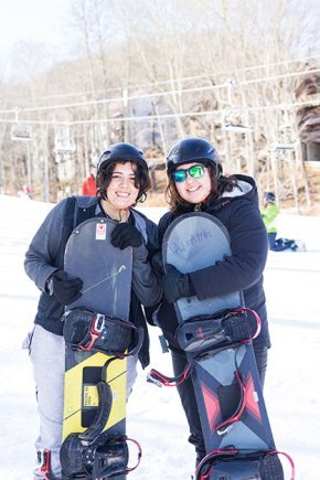 Demmi Ramos and Christina Fisher on a snowy slope holding snowboards