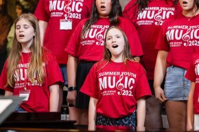 Students wearing red music camp t-shirts sing together in the choir