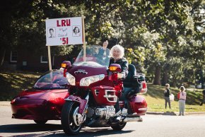 Joe Shumate, with Kathleen Tucker in the sidecar, rides a red Honda Gold Wing in the 2025 Homecoming Parade