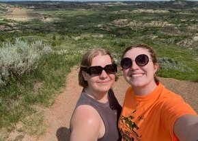 Kaylyn and Amelia take a selfie in front of a prairie landscape.