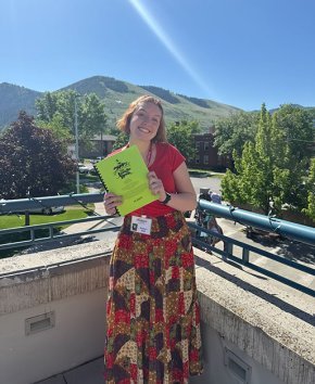 Kaylyn Hall with a copy of The Jungle Book script in front of a mountain in Missoula.
