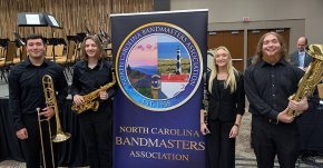 Brysen Rodriguez, Cody Stagner, Lindse Gustafson and Aaron Hollar surround a Bandmasters banner