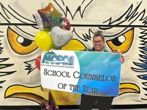 Lauren Mena holds a banner declaring her School Counselor of the Year