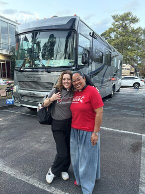 Melanie Dobson and Antoinette Gaboton-Moss in front of the monks' team motorcoach