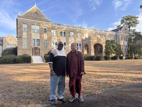 Perry Bradley with one of the monks in front of Beam Hall in morning sunlight