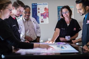 Professors and PA studies students gather around a light table to look at imaging