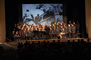 The A Cappella choir performs onstage in front of photos from the Freedom Rides